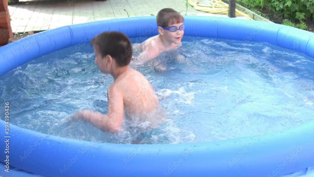 Two boys bathe and frolic in the pool in the summer, splashing water. Two boys bathe and frolic in the pool in the summer, splashing water.