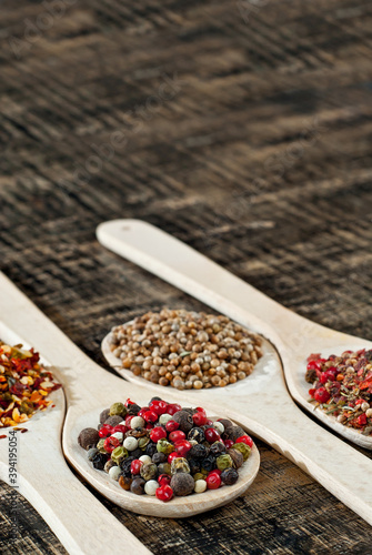 A mixture of various spices in a wooden spoon. Spices and seasonings on an old shabby board. Mix on a pile close up. Place for text and copy space near the spoon.