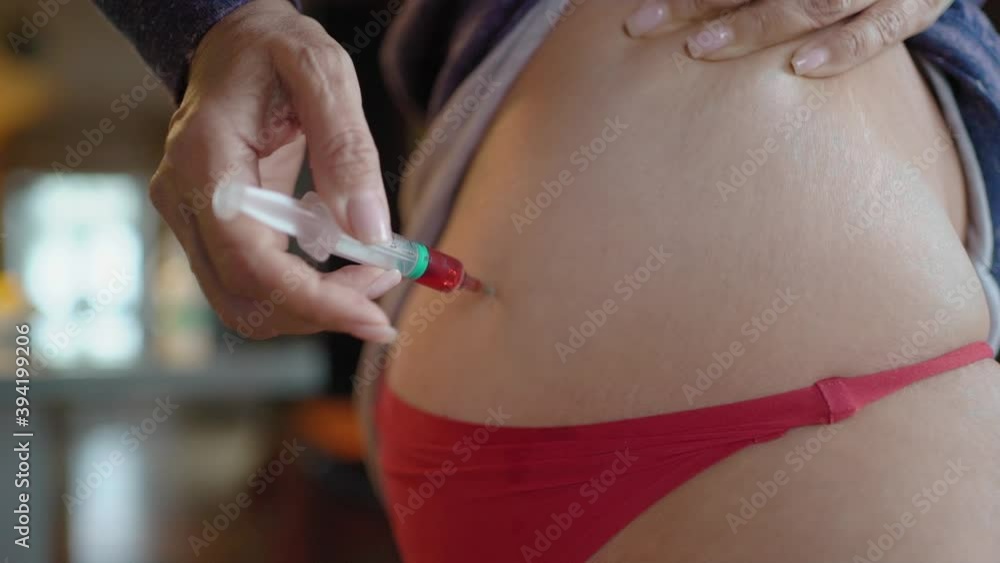 A mature woman gives herself an injection with Vitamin B, a woman sits at home with Covid-19 and gives herself a close-up syringe injections.The woman makes an injection into the intramuscularly. A mature woman gives herself an injection with Vitamin B, a woman sits at home with Covid-19 and gives herself a close-up syringe injections.The woman makes an injection into the intramuscularly.