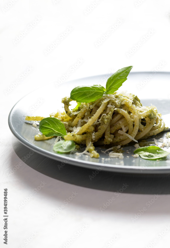 Spaghetti al pesto, basilico, noci e parmigiano isolato su un piatto. Avvicinamento. Messa a fuoco selettiva