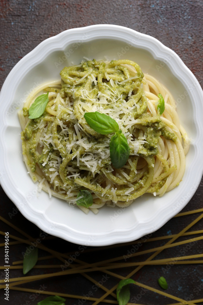Spaghetti di pasta al pesto e foglie di basilico fresco. Sfondo scuro. Messa a fuoco selettiva