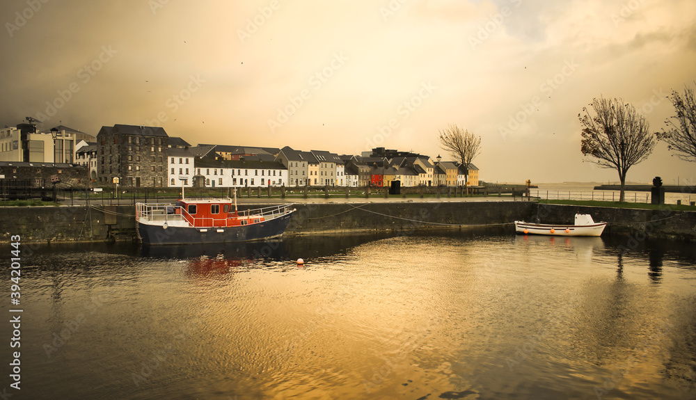 Boats and houses at cloudy golden hour at Claddagh in Galway city, Ireland