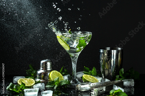 Classic Mojito Cocktail. Ingredients: lime, mint, sugar, ice with splashes on dark background. Freeze motion, drops in liquid splash Cuban national drink