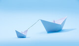 Paper boats - Tugboat or Remorker pulling a big boat on blue background. Little helper concept, Tugboat
