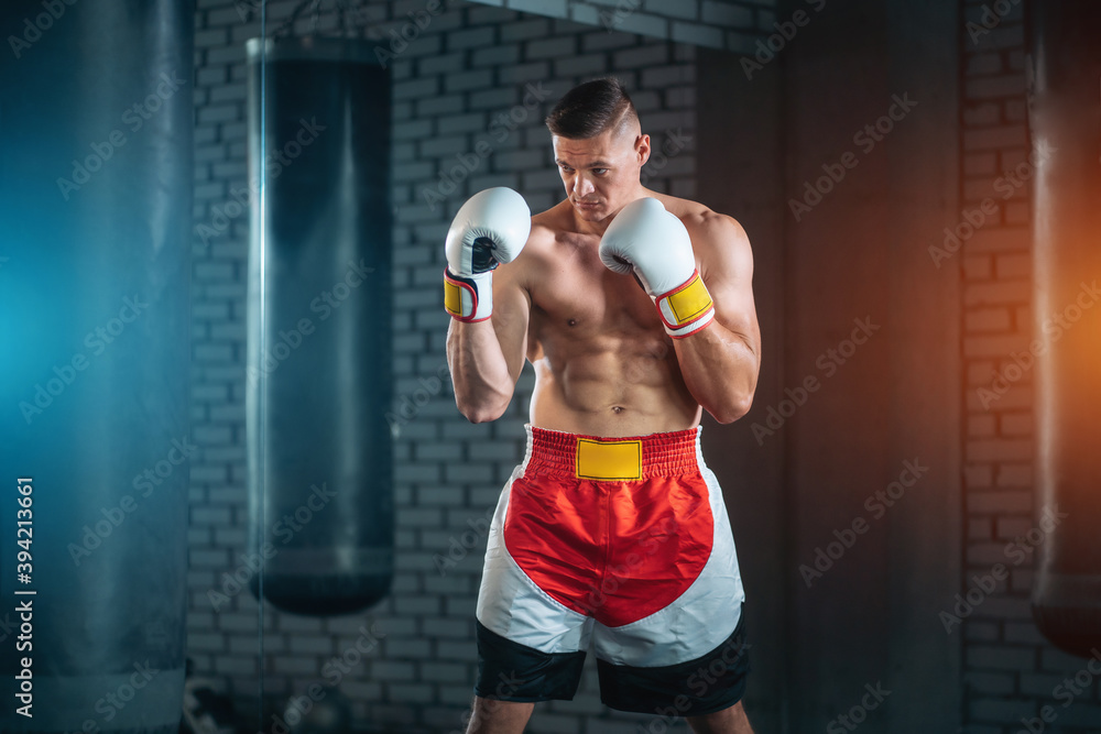 strong sportsman boxer exercising in white gloves at gym