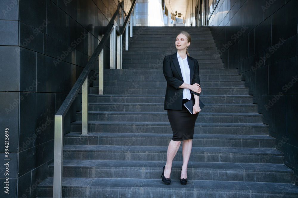 Business woman in on the steps with a notebook in her hand