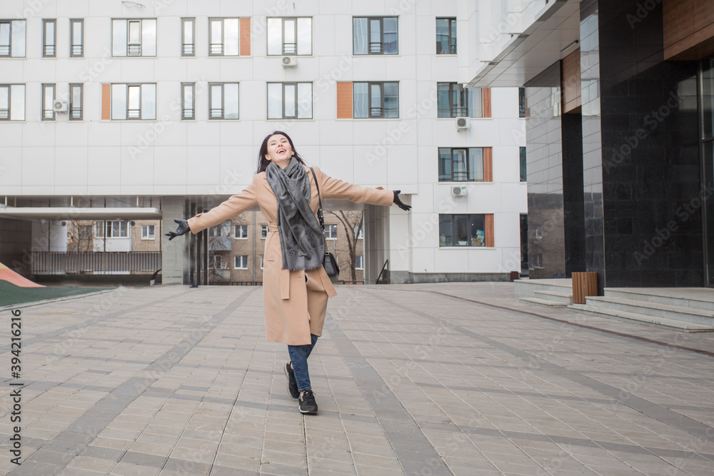 Happy european woman in coat walking in the atumn city