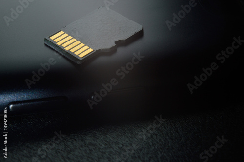 Flash memory storage concept: Micro SD card on the background of a smartphone. A memory card is used to store digital information in portable electronic devices such as mobile phones, tablets, etc.