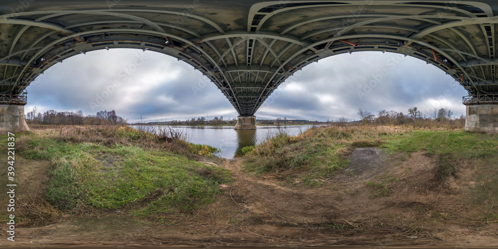 Fototapeta premium full seamless spherical hdri panorama 360 degrees angle view under steel frame construction of huge bridge across river in cloudy weather in equirectangular projection. VR AR content