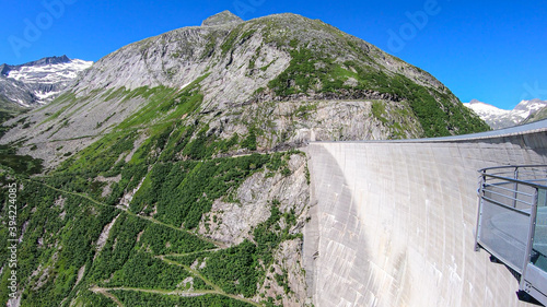 A Kölnbreinsperre dam in Austria. The dam is build in high Alps. The lake stretches over a vast territory. The dam is surrounded by mountains. In the back there is a glacier. Controlling the nature photo