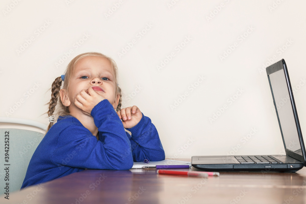 Little girl in a blue blouse sits in front of a laptop and looks at the camera. The child rested her head on her arm
Little girl in a blue blouse sits in front of a laptop and looks at the camera. The child rested her head on her arm