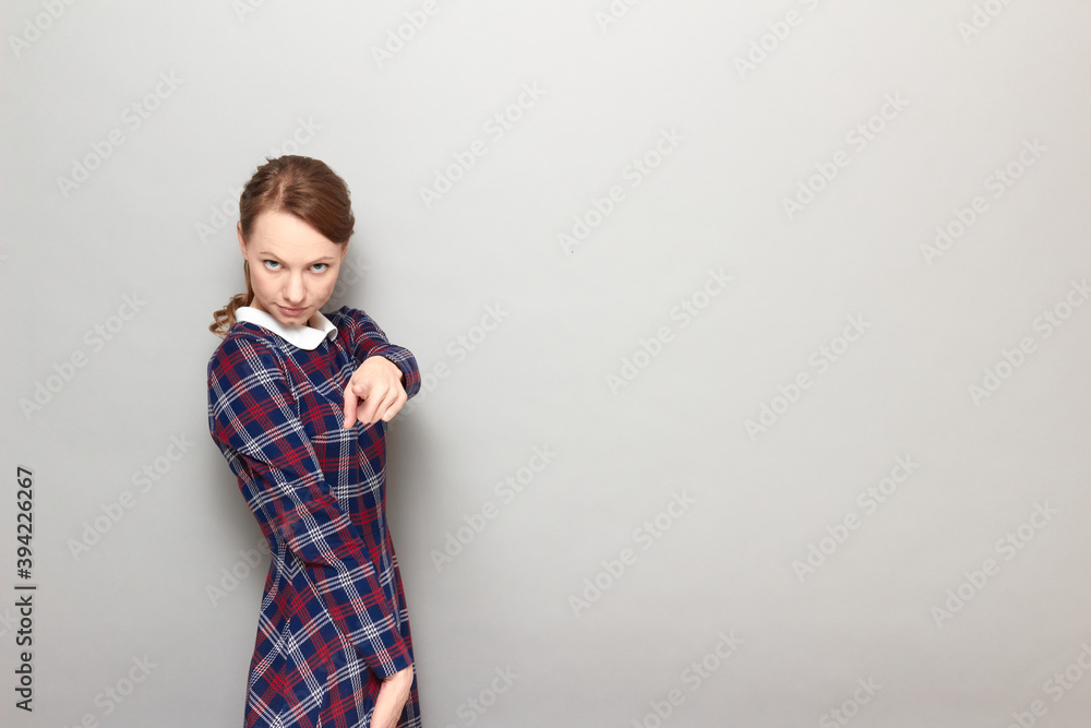 Portrait of serious girl pointing with index finger at you