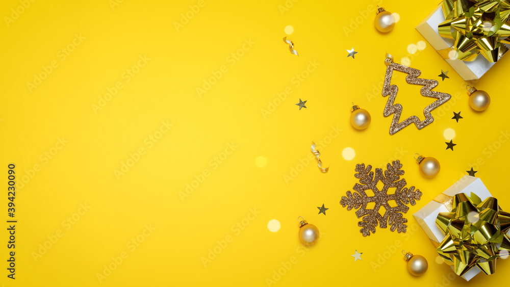 Christmas gift. White gifts with golden color bow, yellow balls and sparkling lights in xmas decoration on yellow background for greeting card. Xmas backdrop with space for text.