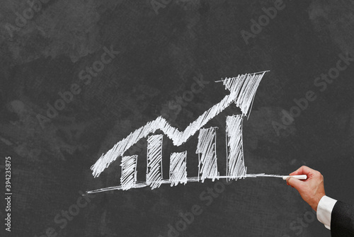 Mann zeichnet auf Tafel Balken Diagramm und Pfeil nach oben photo