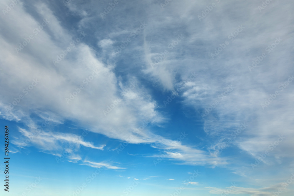 Beautiful blue sky background at daylight with white streched spindrift clouds. Wide angle photo shot