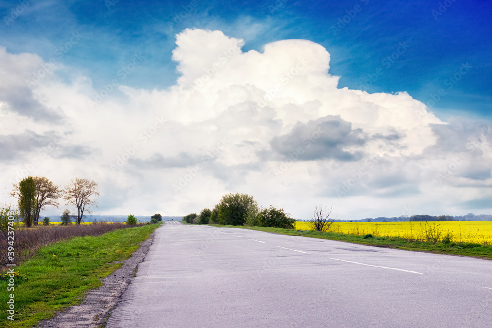 Highway among the fields and picturesque blue sky with white cloud