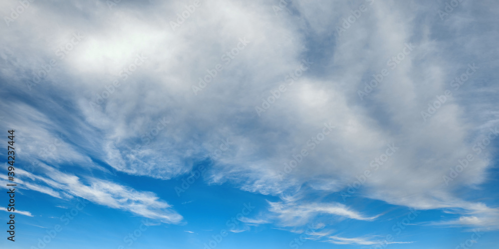 Beautiful blue sky background at daylight with white streched spindrift clouds. Panoramic banner