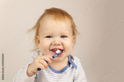 little baby practicing brushing teeth on his own. Kid with red hair brushes teeth. Oral hygiene.