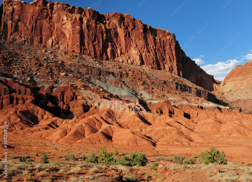 View To A Colorful Butte From Scenic Drive Road Capitol Reef National Park In The Late Afternoon Sun On A Sunny Summer Day With A Clear Blue Sky And A Few Clouds View To A Colorful Butte From Scenic Drive Road Capitol Reef National Park In The Late Afternoon Sun On A Sunny Summer Day With A Clear Blue Sky And A Few Clouds