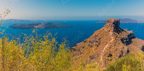Skaros rock protrudes from Santorini's caldera rim with views towards Nea Kameni in summertime