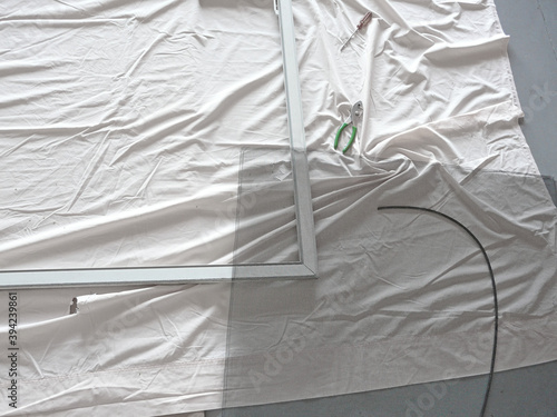 Repairing Sliding Screen Door with Spline. A new replacement wire mesh panel, spline, and tools are assembled on an old sheet for a project to repair a damaged sliding garage screen door with a metal 