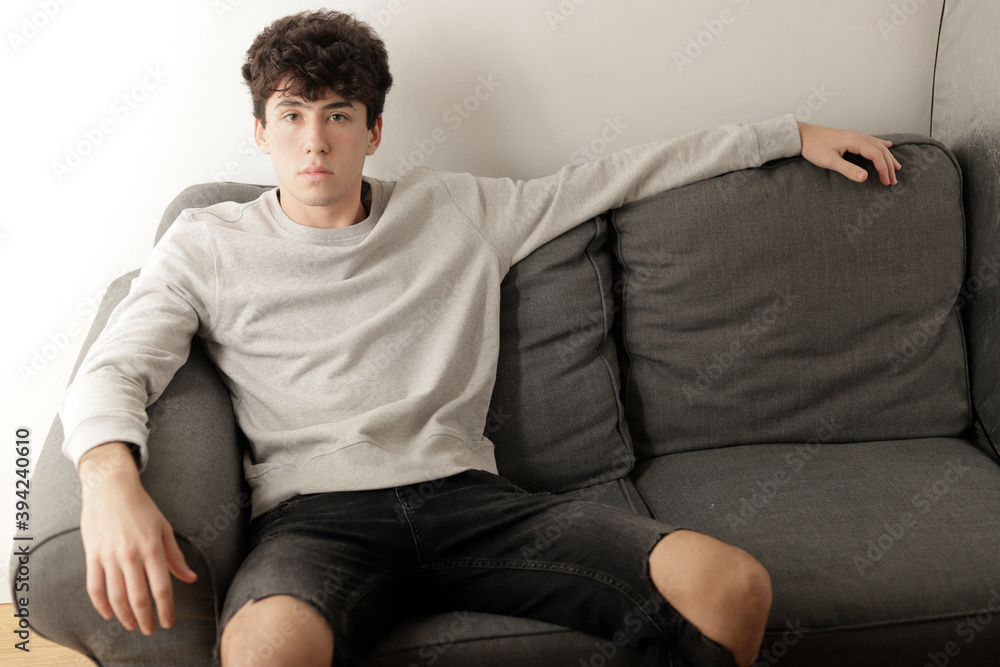 chico sentado comodamente en el sofá de su casa mirando a cámara chico sentado comodamente en el sofá de su casa mirando a cámara