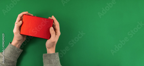 Man holding a red gift box seasonal theme photo banner with negative space, green background