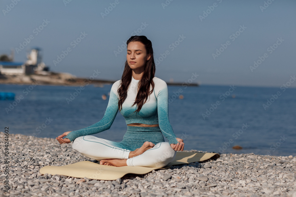 Fototapeta premium Caucasian young woman practicing yoga at seashore