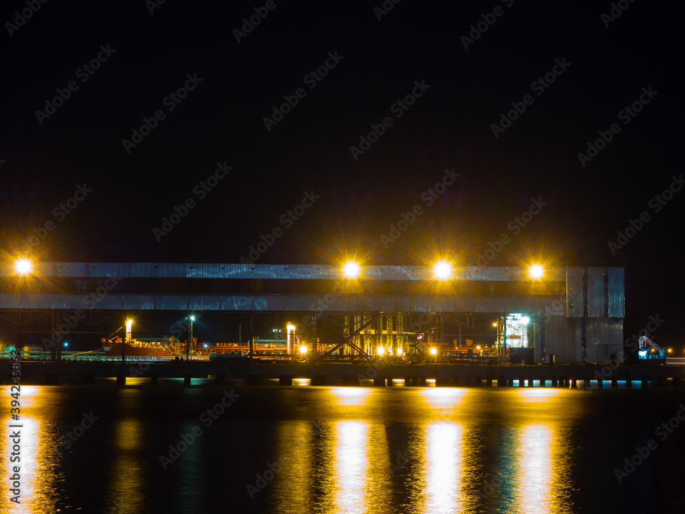 Night view of a seaport with a metal structure illuminated by bright lights