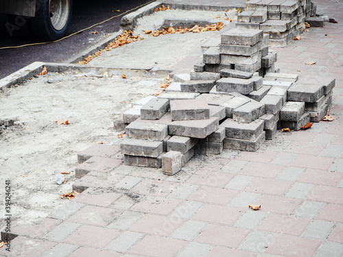 Sidewalk with not fully laid out paving slabs and stacked tiles on it