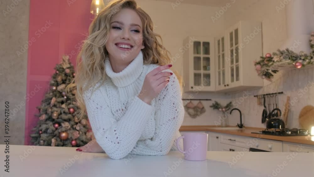 A beautiful blonde in a white sweater dances and rejoices in the kitchen. A beautiful blonde in a white sweater dances and rejoices in the kitchen.