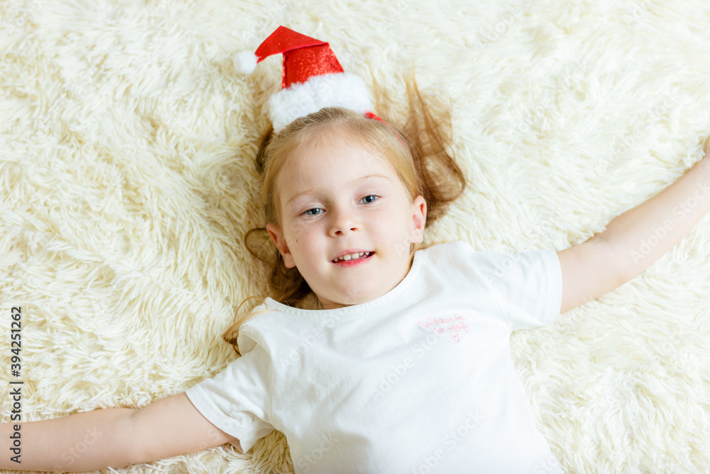 Fototapeta premium girl in red cap is lying on white blanket