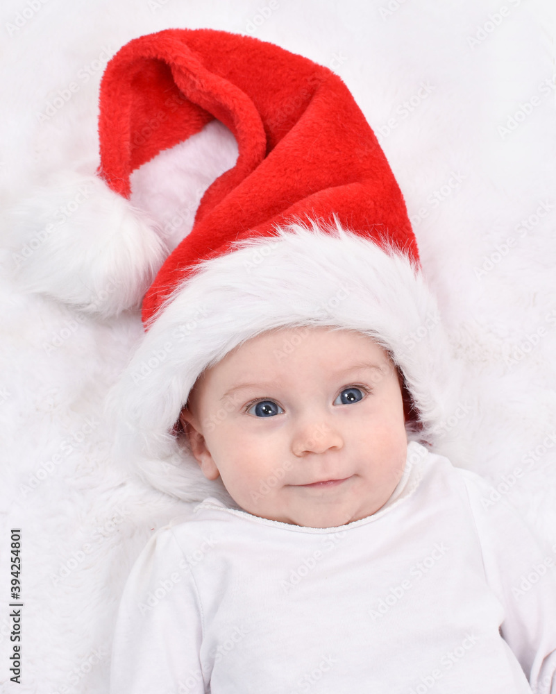 Christmas baby. Cute four month old baby in a Santa Christmas hat lying on back on white background and smiling. Christmas baby. Cute four month old baby in a Santa Christmas hat lying on back on white background and smiling.