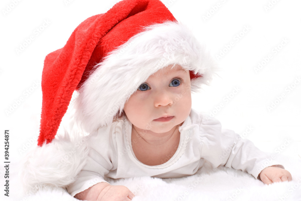 Christmas mood, baby. Cute four month old caucasian baby in a red Santa Claus hat lying on stomach, on a white background. Christmas card. Christmas mood, baby. Cute four month old caucasian baby in a red Santa Claus hat lying on stomach, on a white background. Christmas card.