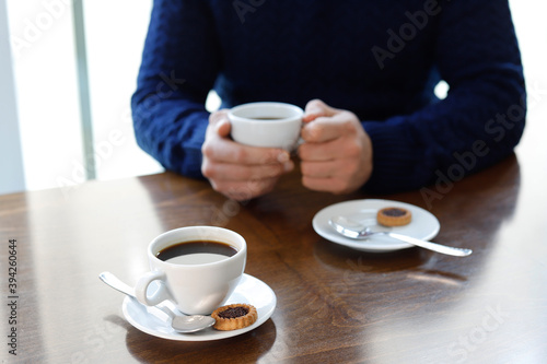 Two cups of coffee withma n hands on the wooden table in cafe background