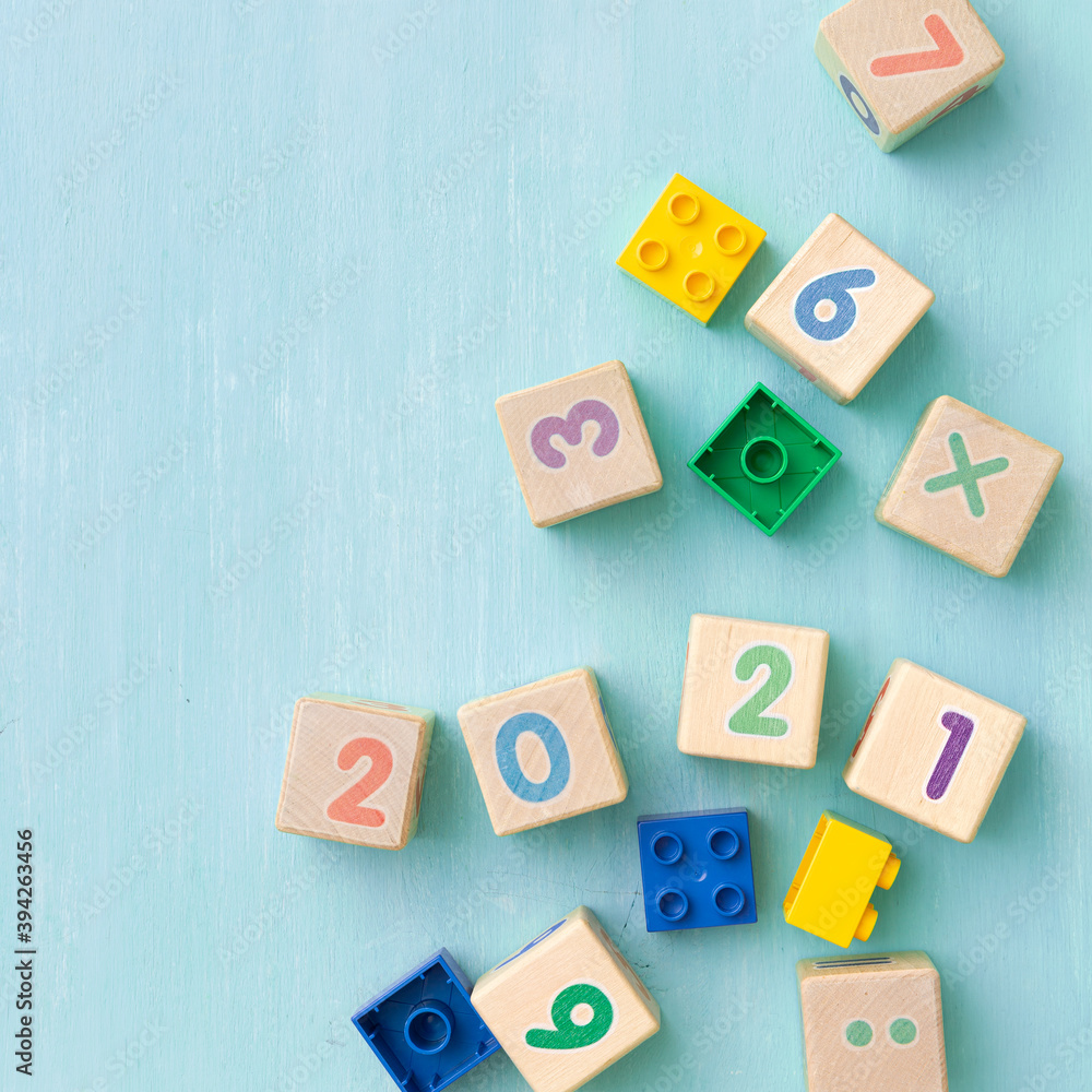 Colorful plastic and wooden cubes with numbers scattered on a blue wooden table. Top view of children's toys and other equipment. Educational games for children. Cubes with numbers 2021. Colorful plastic and wooden cubes with numbers scattered on a blue wooden table. Top view of children's toys and other equipment. Educational games for children. Cubes with numbers 2021.