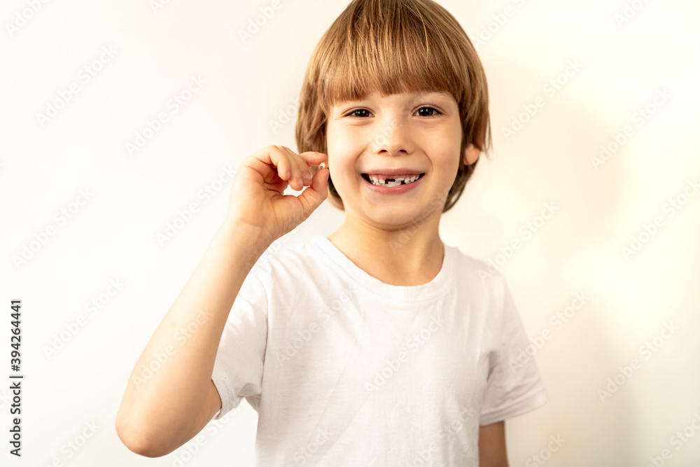 little toothless boy holds a fallen milk tooth in his hand and smiles little toothless boy holds a fallen milk tooth in his hand and smiles