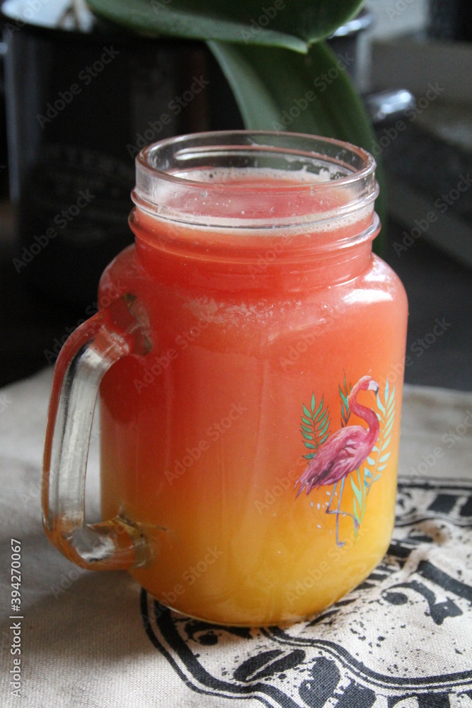 a glass with a handle and yellow-orange juice inside a glass with a handle and yellow-orange juice inside