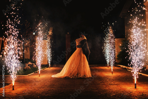 Newlyweds kiss on the background of a pyrotechnic show, fireworks fountains