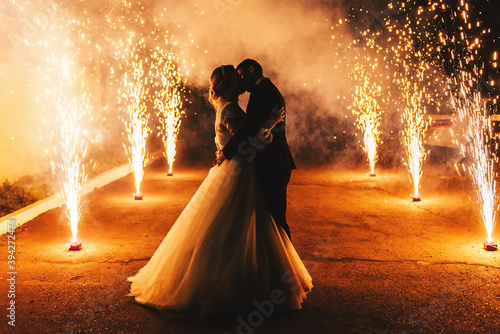 Newlyweds kiss on the background of a pyrotechnic show, fireworks fountains