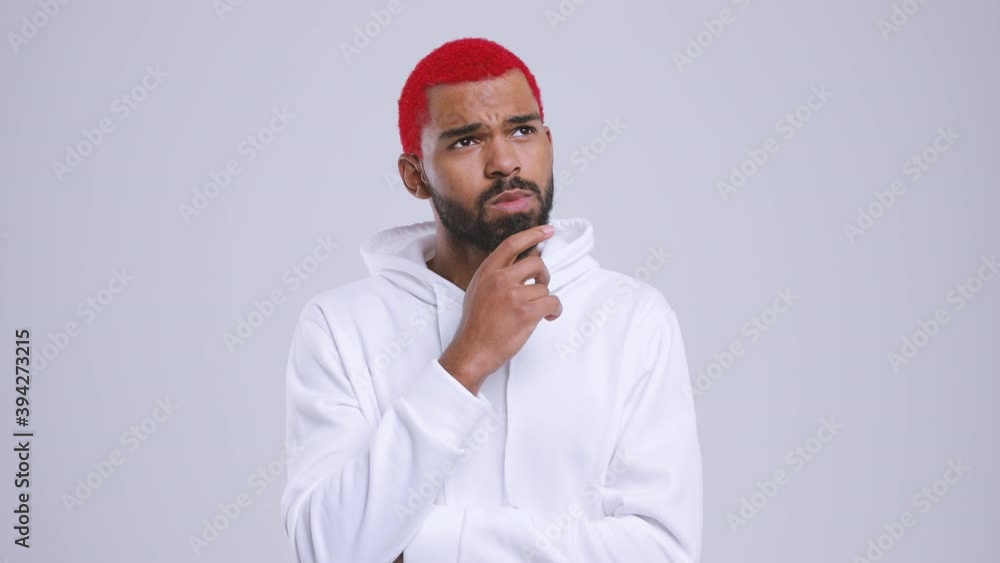 Puzzled pensive young bearded african american man with red hair in streetwear hoodie isolated on white color background in studio. People lifestyle concept. Looking aside up put hand prop up on chin Puzzled pensive young bearded african american man with red hair in streetwear hoodie isolated on white color background in studio. People lifestyle concept. Looking aside up put hand prop up on chin