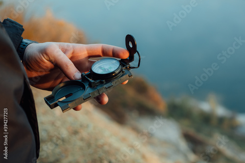 A young man uses a military compass for orientation in nature, talking on the phone, surrounded by fog.