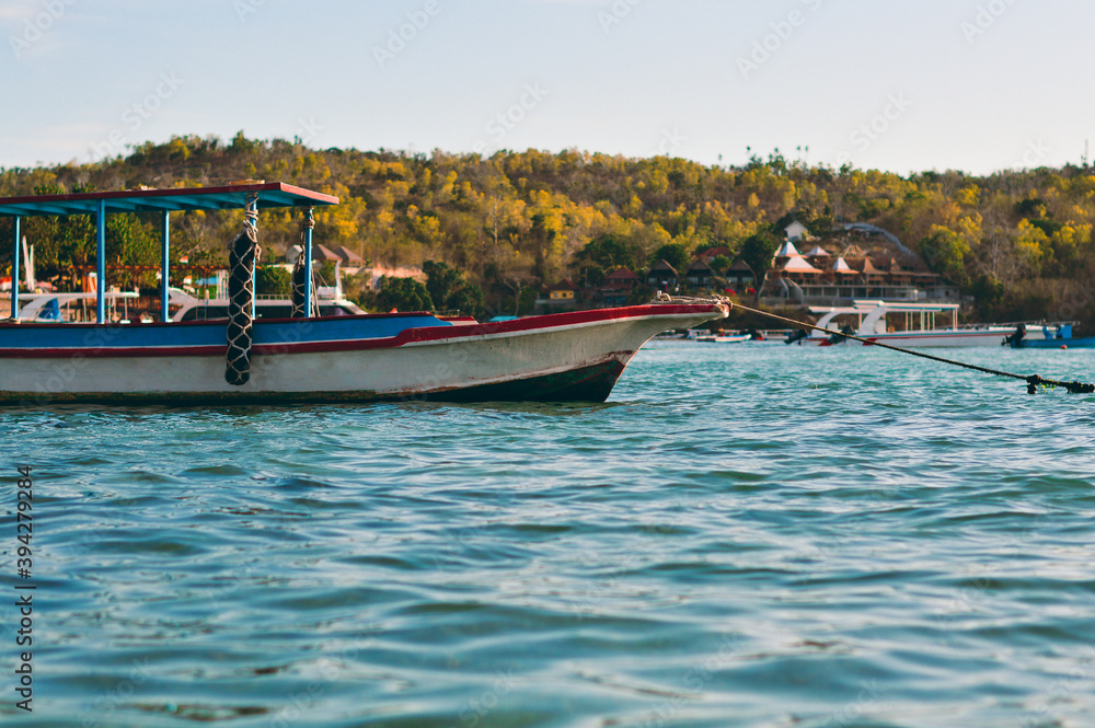 Image of a traditional boat ankered at the harbour of toya pakeh, Nusa Penida, Bali, Indonesia during sunset. Forest and a bautiful guesthouse in the background. Image of a traditional boat ankered at the harbour of toya pakeh, Nusa Penida, Bali, Indonesia during sunset. Forest and a bautiful guesthouse in the background.