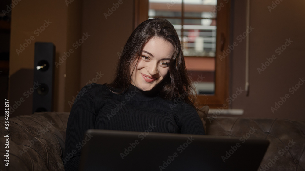 Beautiful sweet girl sitting on the sofa using laptop, technology concept Beautiful sweet girl sitting on the sofa using laptop, technology concept