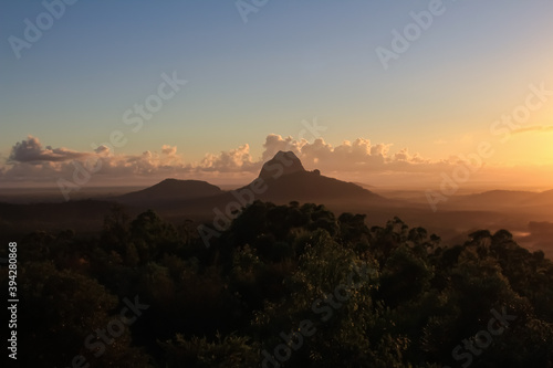 Image of the Glass House Mountains during sunrise in Queensland, Australia with great cloud formations and beautiful light shining through the morning fog. photo