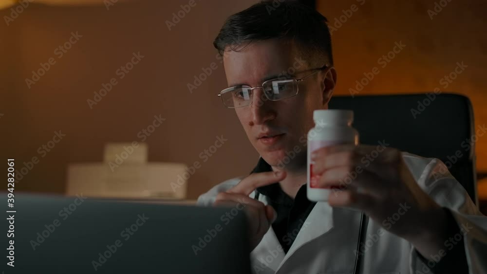 Close-up doctor portrait, talking on-line with patient from home during pandemic is going. Confident doctor showing jar with medicines as good stuff for client. Professional online consultation. Close-up doctor portrait, talking on-line with patient from home during pandemic is going. Confident doctor showing jar with medicines as good stuff for client. Professional online consultation.