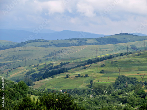 Mountain slopes with power lines and green rural fields and trees