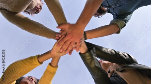 The team puts their hands together and shakes against the sky. Unity of a multinational company