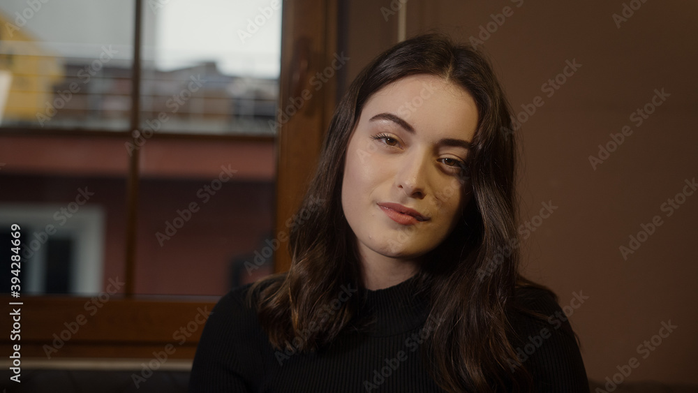 Beautiful dressed girl sitting on sofa looking at camera close-up, smiling and relaxing, home health and comfort concept Beautiful dressed girl sitting on sofa looking at camera close-up, smiling and relaxing, home health and comfort concept