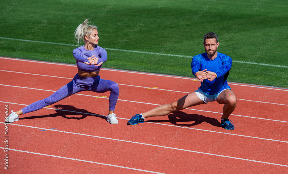 Obraz premium fitness sport man and woman warming up and stretching together on outdoor stadium racetrack wearing sportswear, coach